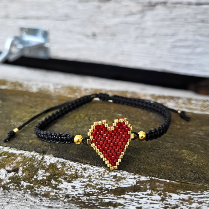 Sort armbånd med rødt hjerte lavet af Miyuki-perler, gulddetaljer og justerbar lukning i macramé – håndlavet og fyldt med personlighed.