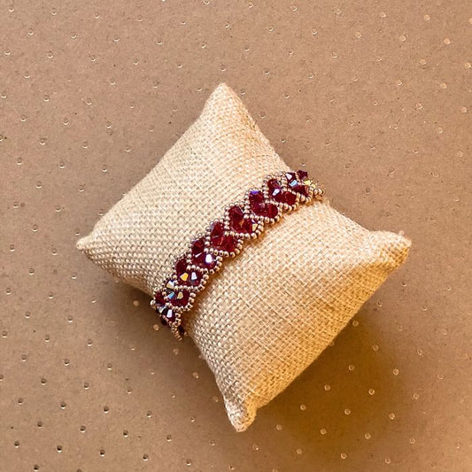 Armbånd med røde krystalhjerter og små perler i røde og guldtoner – et håndlavet design med romantisk udtryk og glitrende detaljer.