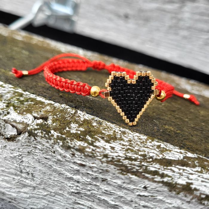 Sort armbånd med sort hjerte lavet af Miyuki-perler, gulddetaljer og justerbar lukning i rød macramé – håndlavet og fyldt med personlighed.