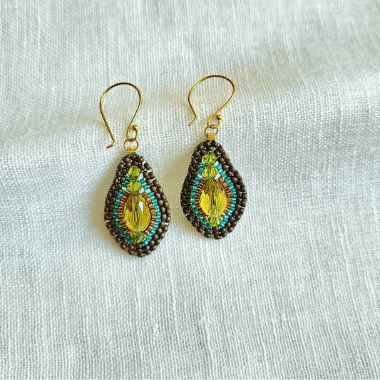 Dråbeformede håndlavede øreringe med gul krystal – turkisblå og gyldnefarvede perler indrammer stenen og fremhæver det mystiske skær og den elegante kontrast.