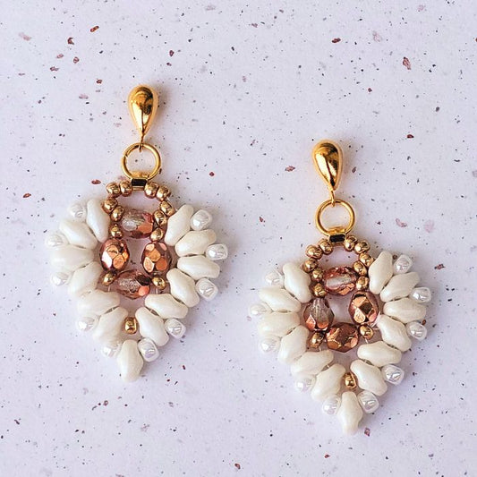 Romantiske øreringe i hjerteform, vævet med hvide glasperler og funklende krystaller. Elegant og detaljeret design, perfekt til særlige anledninger