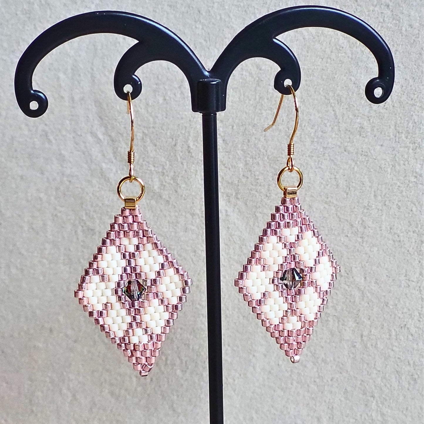 Små håndvævede diamantformede øreringe i hvid og lyserød nuancer – elegante Miyuki-perler i geometrisk mønster med diskret glans
