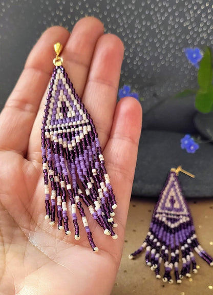 Lange trekantede øreringe med detaljeret geometrisk mønster i lilla og bordeaufarvede perler – håndvævet design med elegante frynser